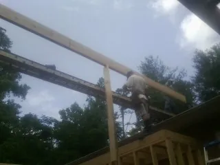Carpenter setting a ridge beam over a new addition frame — Ice Dam Removal by Roofing Brothers in Valentines
