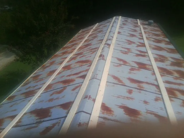Rusted metal roof panels with new wood purlins before replacement — Storm Damage Roof Repair in Valentines by Roofing Brothers