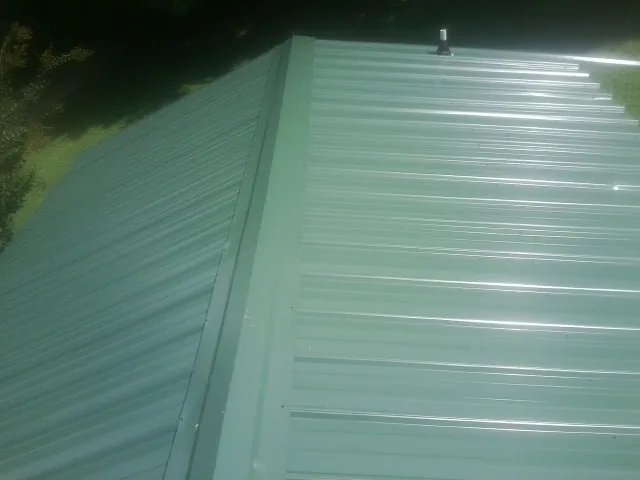 New green metal panels meeting at the ridge of a roof — Flat Roof Repair work by our crew in Valentines