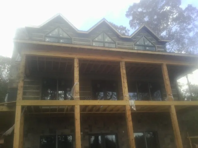 Dormers and porch framing on a large log home under construction — Roof Coating work by our crew in Valentines