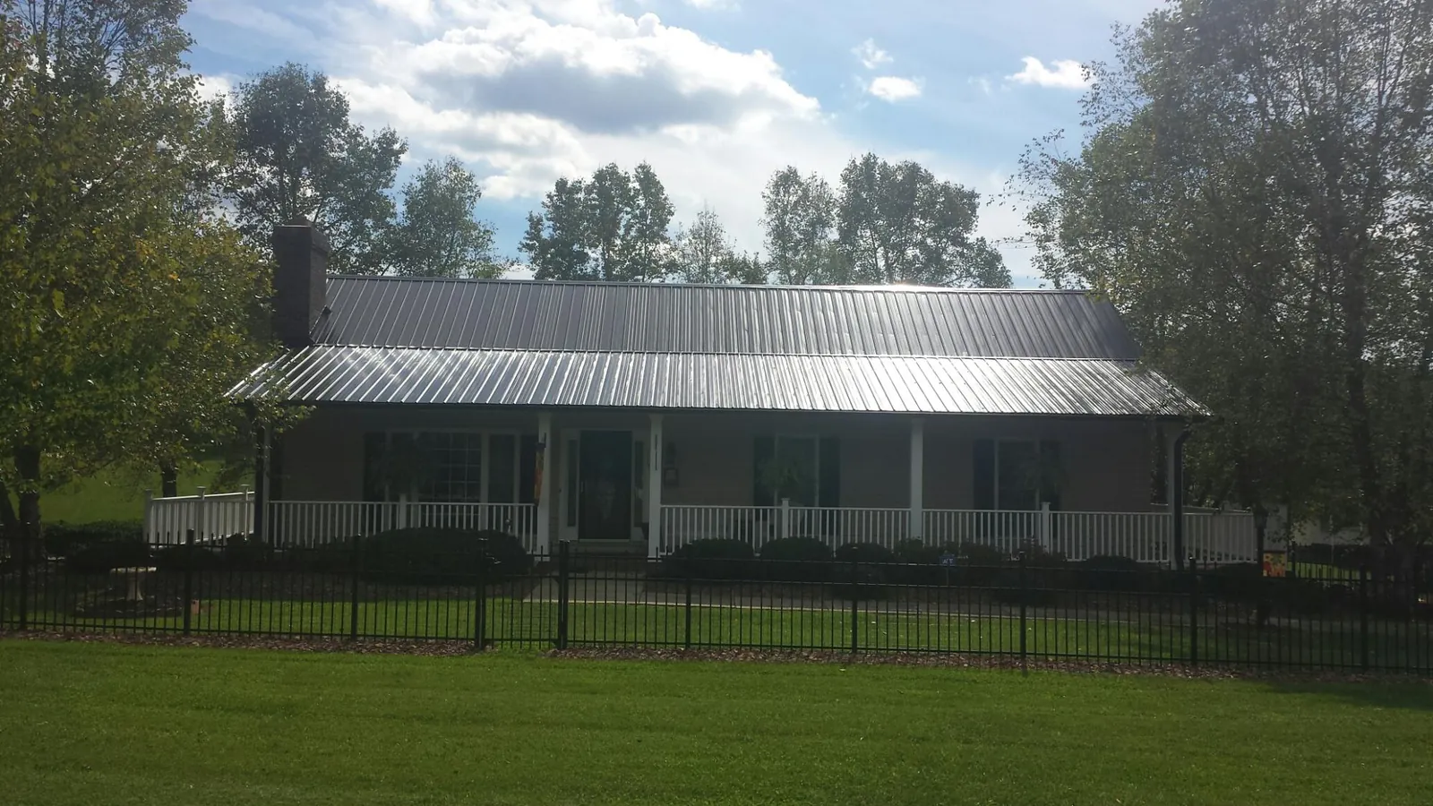 Gray metal roof on a brick ranch with a full width front porch — Gutter Guard Installation work by our crew in Valentines