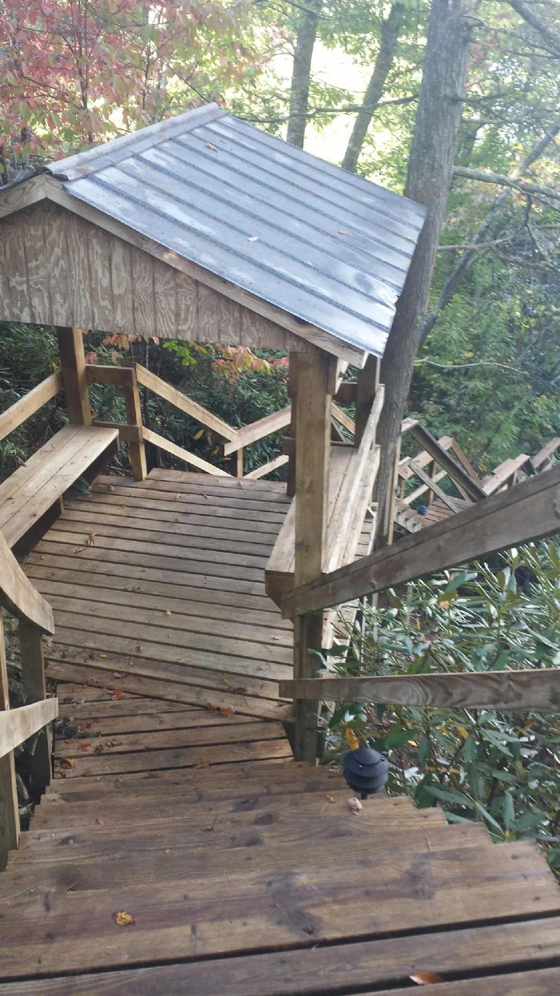 Metal roofed shelter over wooden steps on a wooded walkway — Skylight Repair & Installation work by our crew in Valentines