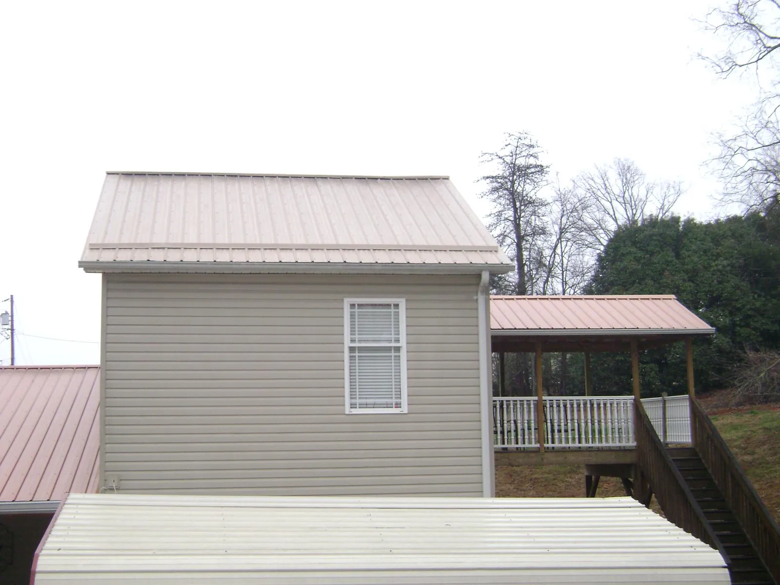 Tan metal roofs on a two story addition and attached porch, from a Roof Replacement job in Valentines